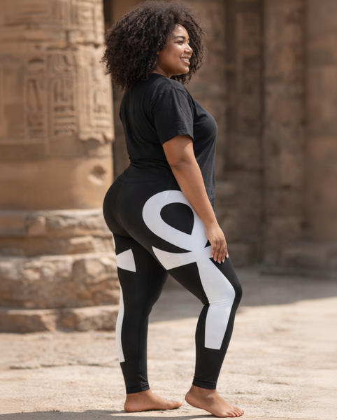 Woman wearing black and white leggings with a large 'ANKH' design, standing in front of stone steps.