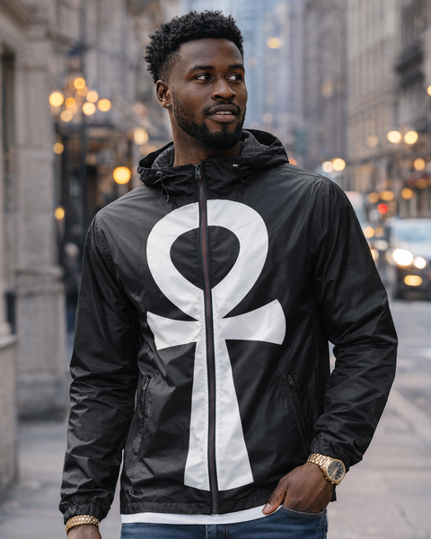 Man wearing a black jacket with a white ANKH symbol on a city street