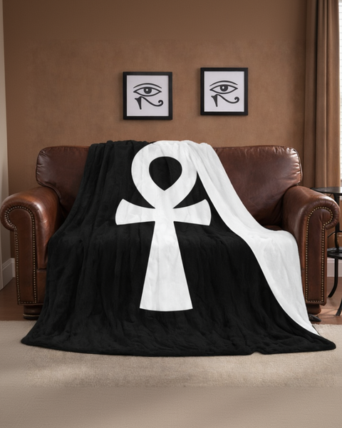 Black and white ankh symbol blanket draped over a brown leather sofa in a living room.