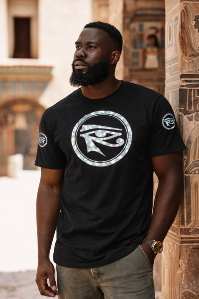 Man wearing a black t-shirt with a silver horus logo in an ancient Egyptian setting