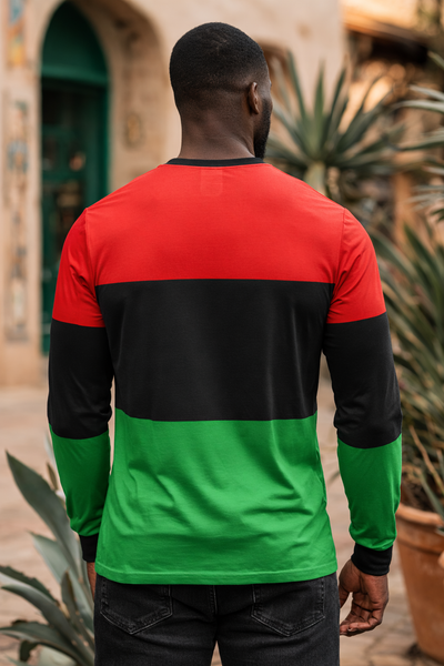 Person wearing a red, black, and green long-sleeve shirt with plants and a building in the background