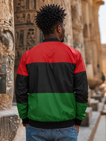 Person wearing a red, black, and green jacket standing in front of ancient stone carvings.