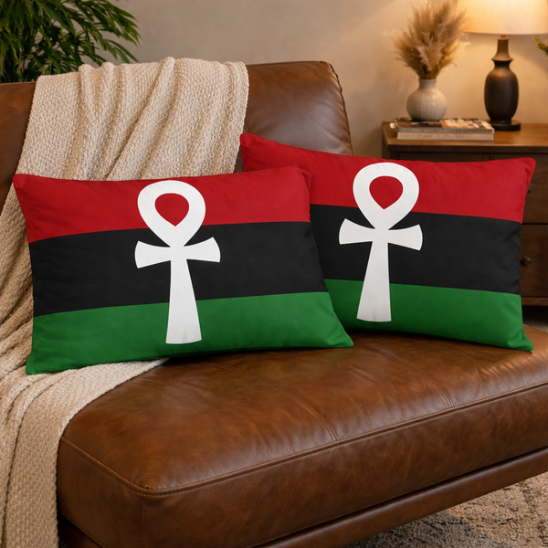 Two pillows with a white ANKH symbol on a red, black, and green background on a brown couch.