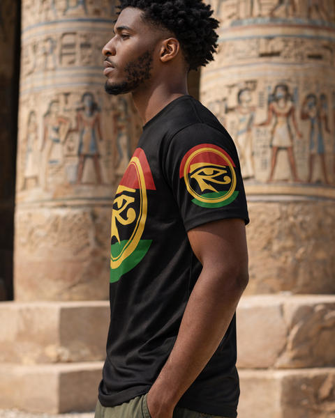 Man wearing a black t-shirt with colorful EYE OF HORUS RED BLACK AND GREEN designs in front of ancient Egyptian columns. NUBIAN LUXURIES BRAND
