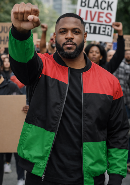 Person wearing a red, black, and green jacket with raised fist at a protest rally.