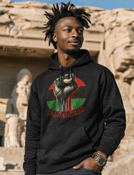Person wearing a black hoodie with a colorful RBG PAN AFRICAN DESIGN in front of ancient ruins.