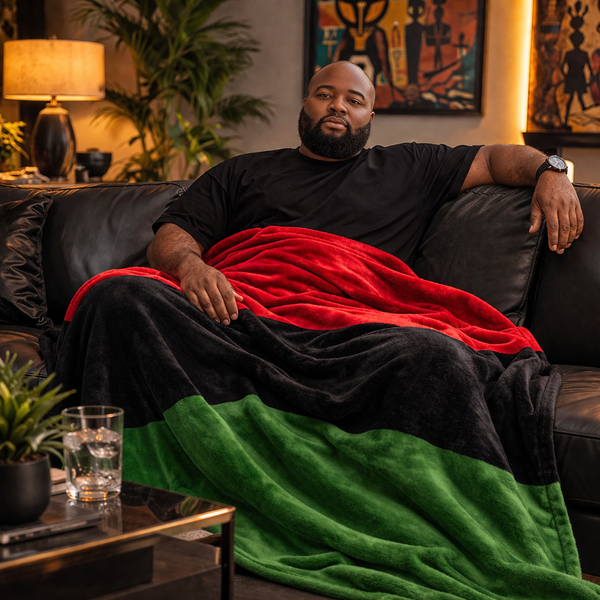 Man sitting on a couch with a Pan-African flag blanket draped over him in a living room setting.