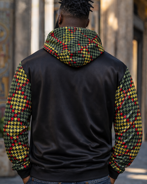 Person wearing a black hoodie with colorful checkered sleeves in an urban setting