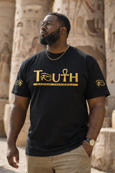 Man wearing a black t-shirt with gold text and symbols in front of ancient Egyptian architecture.