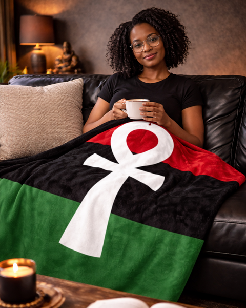 Woman sitting on a couch with a flag-themed blanket, holding a cup.
